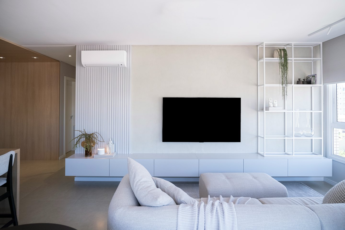 Modernes Wohnzimmer mit großem Fernseher über einem schwebenden Unterhaltungsregal.